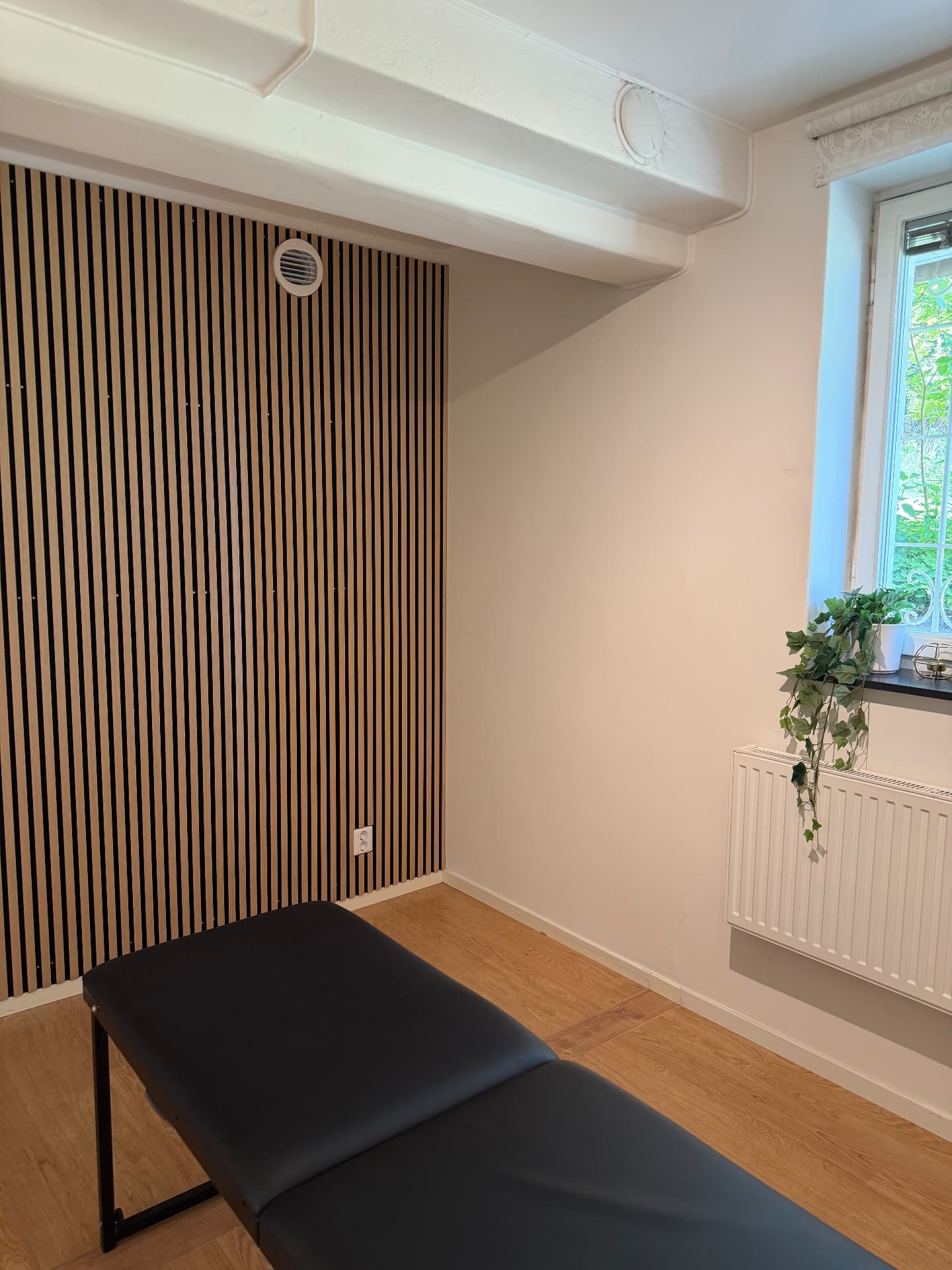 Behandlingsrummet på kiropraktorkliniken i Huddinge med behandlingsbänk och träpanel